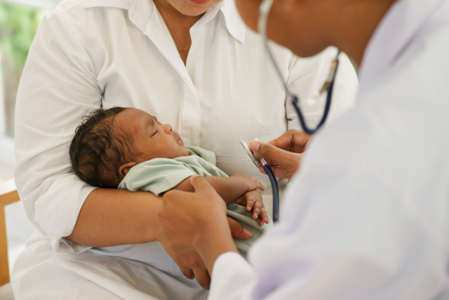 Infant in woman's arms during doctor check up