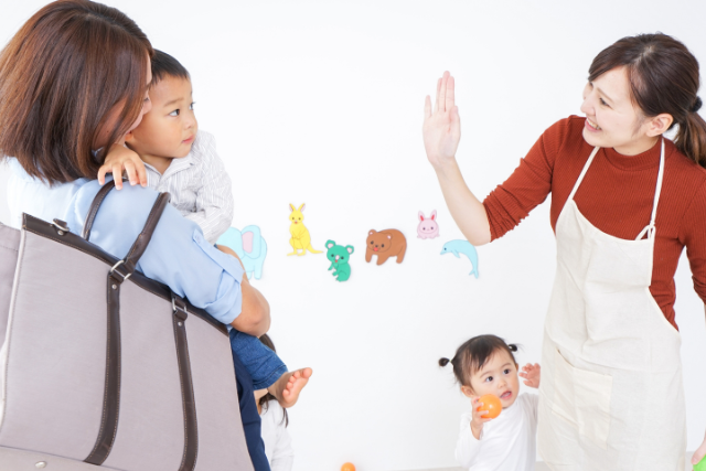 mom dropping son off at daycare with waving teacher